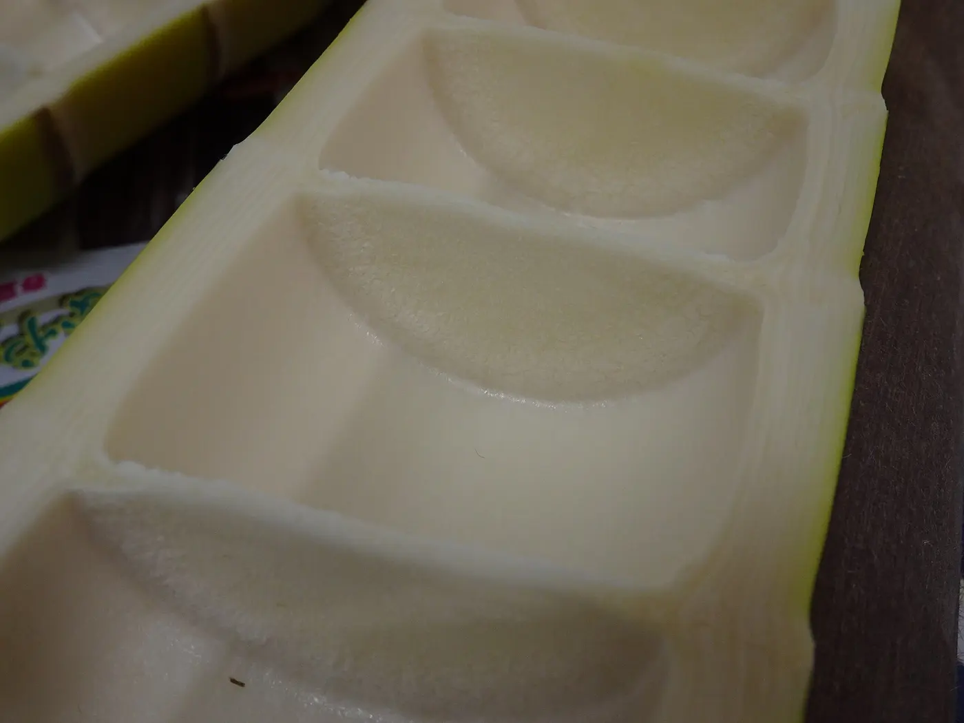 A peeled bamboo shoot cut in half lengthwise, showing a row of chambers separated by white node walls