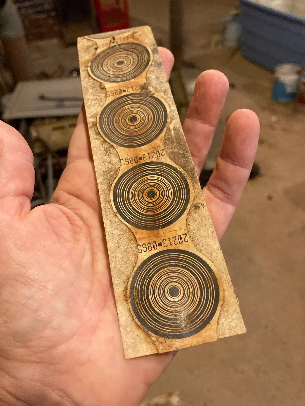 A hand holding a narrow strip of card with four concentric-circle patterns on it
