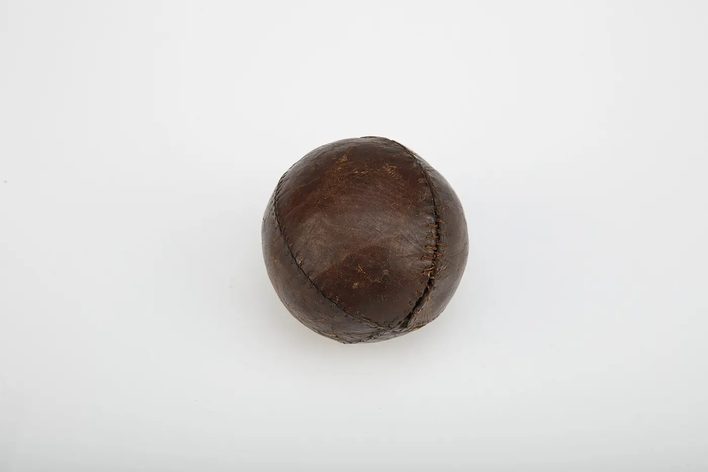 An old “lemon peel” baseball made from a single piece of brown leather sewn around the core