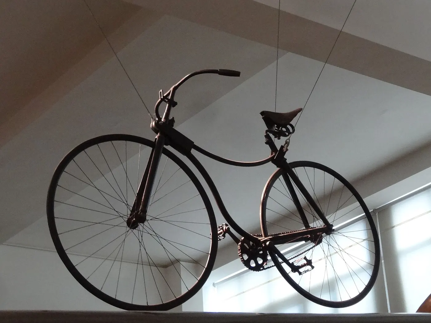 An old bicycle with a slightly larger front wheel and a chain carrying pedal power to the rear wheel