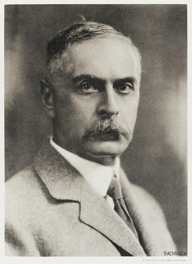 Portrait photograph of an older man with a mustache, wearing a suit and facing the camera