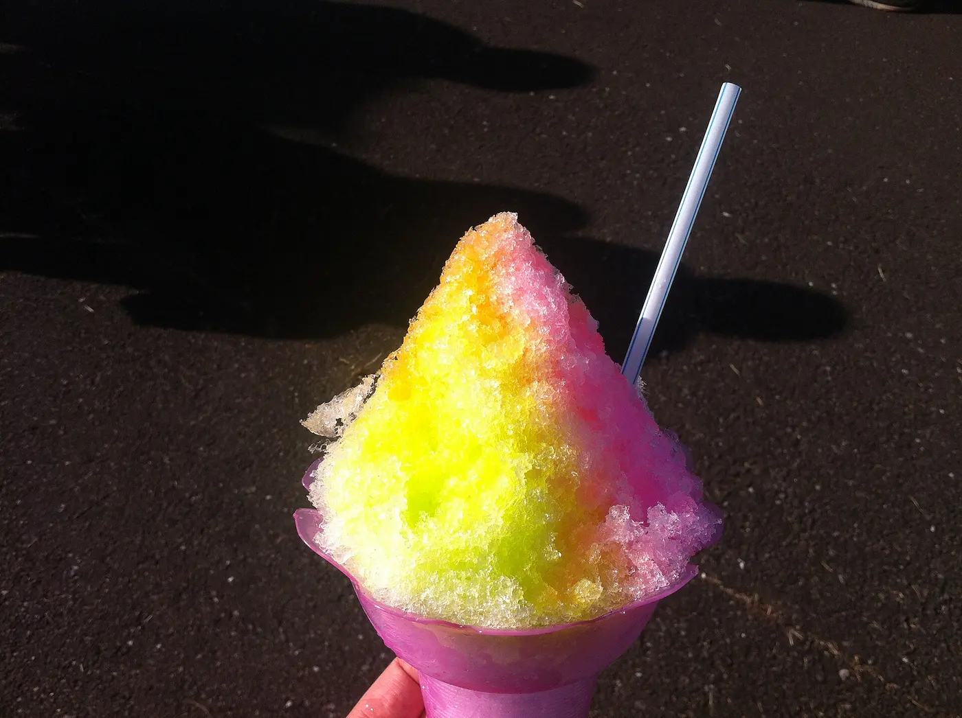 A heaping bowl of shaved ice topped with yellow and pink syrups