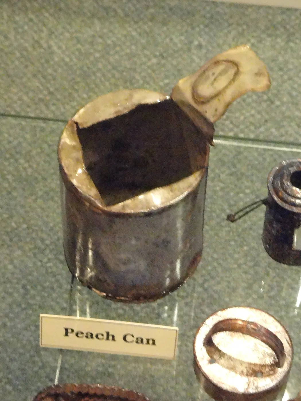 An old metal can with its top cut open in a jagged line and the lid peeled back
