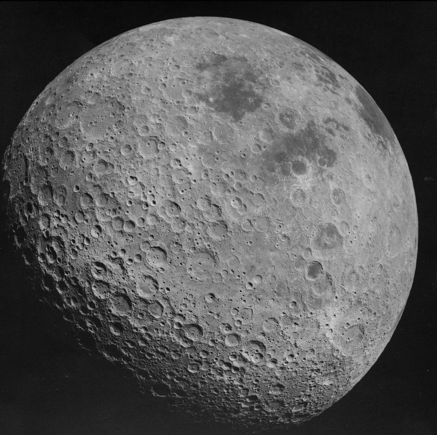 A lunar surface covered in countless craters, with a small dark area visible only near the upper-right edge