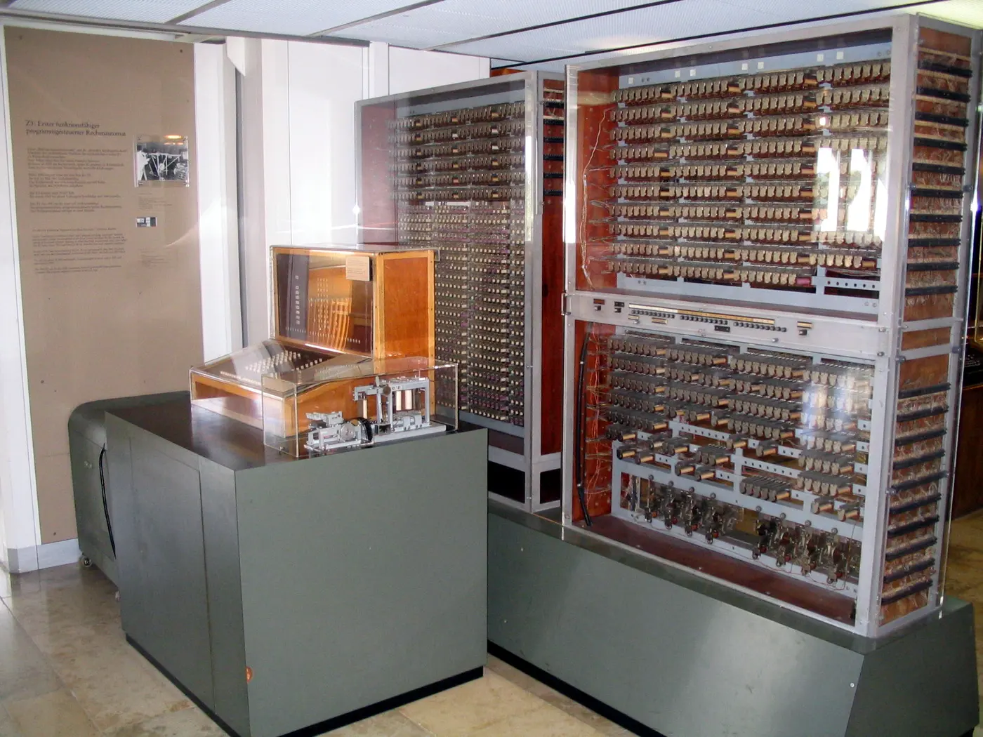 A computing machine on display in a museum, with tall cabinets packed with relays and a control console