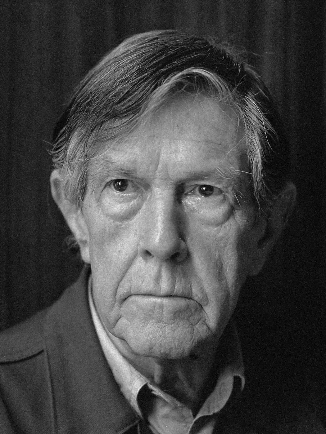 Black-and-white portrait of an older man with graying hair looking straight at the camera