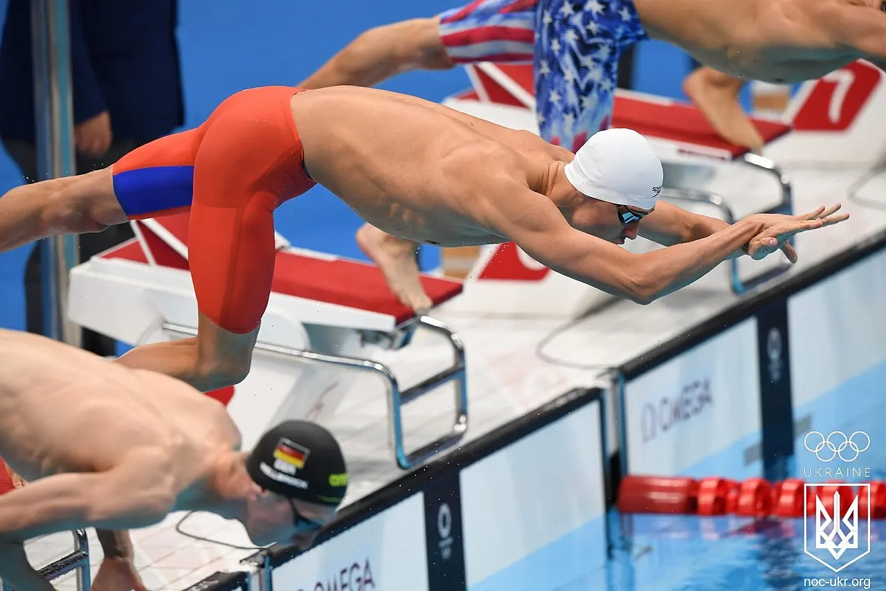 Swimmers diving from the starting blocks into the pool together