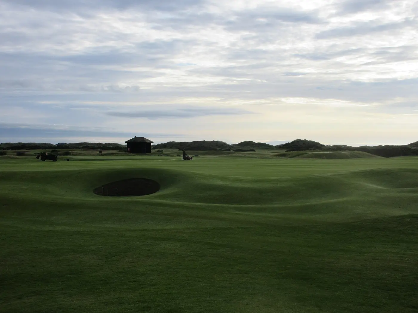 A wide green and the links course stretching around it