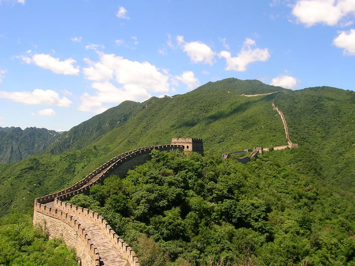 Stone and brick ramparts winding along the ridges of green mountains, punctuated by watchtowers