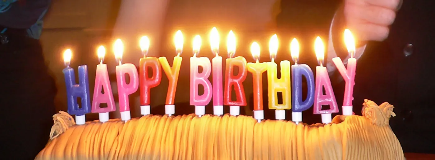 Colorful candles shaped like the letters HAPPY BIRTHDAY burning on a cake