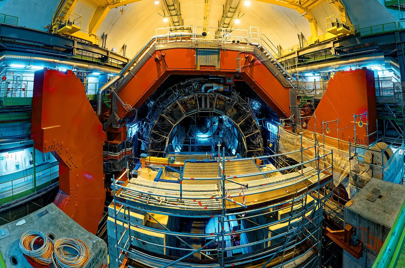 A cylindrical detector surrounded by a huge red frame and scaffolding