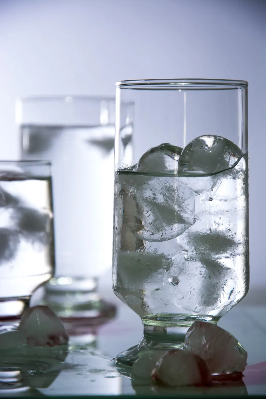 A side view of a glass of water with ice, part of the ice poking above the surface