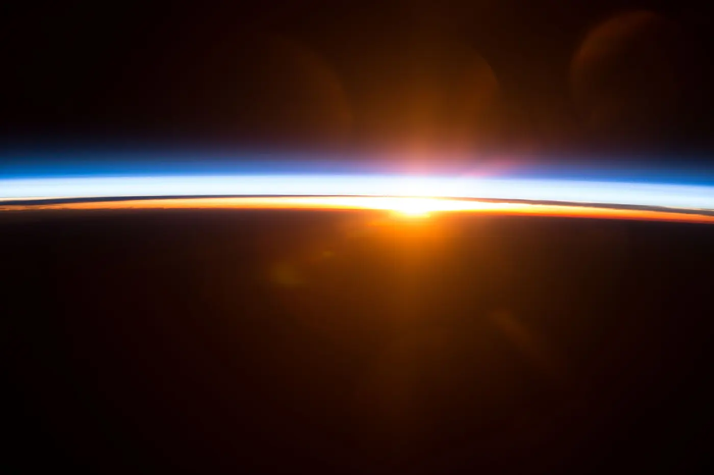 The Sun rising over the dark edge of the Earth along with a thin band of light