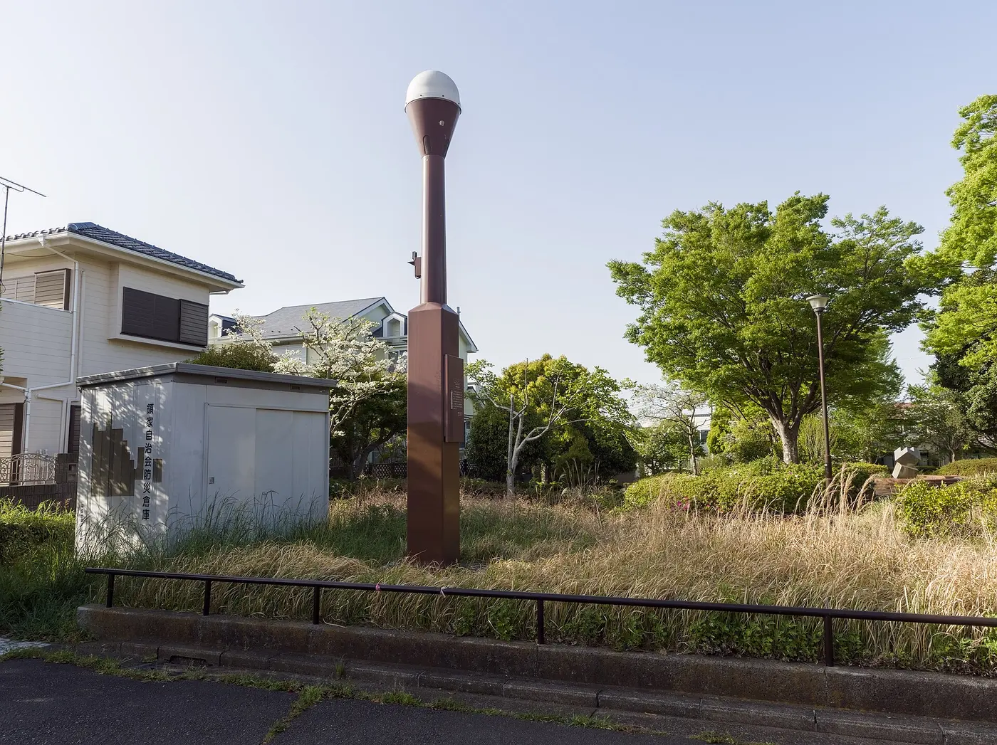 A slender brown pillar topped with a round white cover, standing on a corner of a residential area