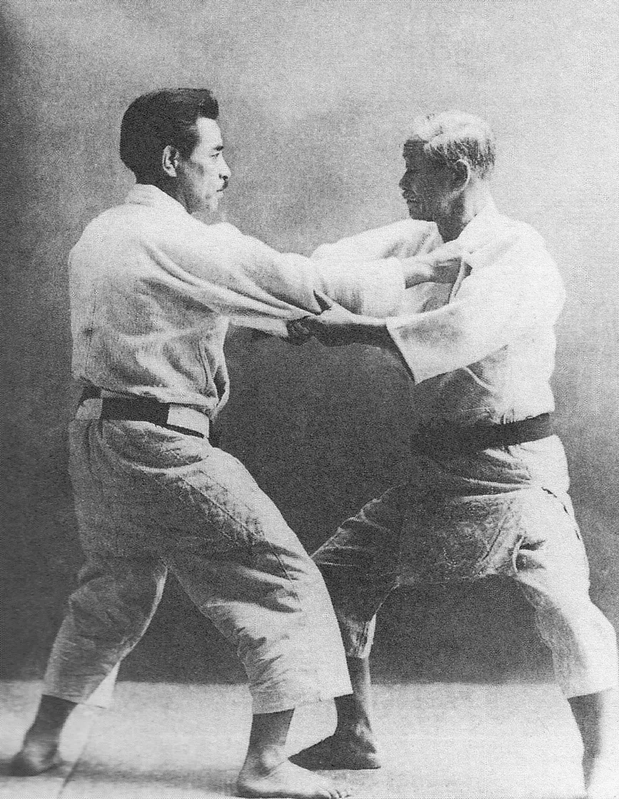 Kanō Jigorō and Mifune Kyūzō in judo uniforms and black belts, gripping each other