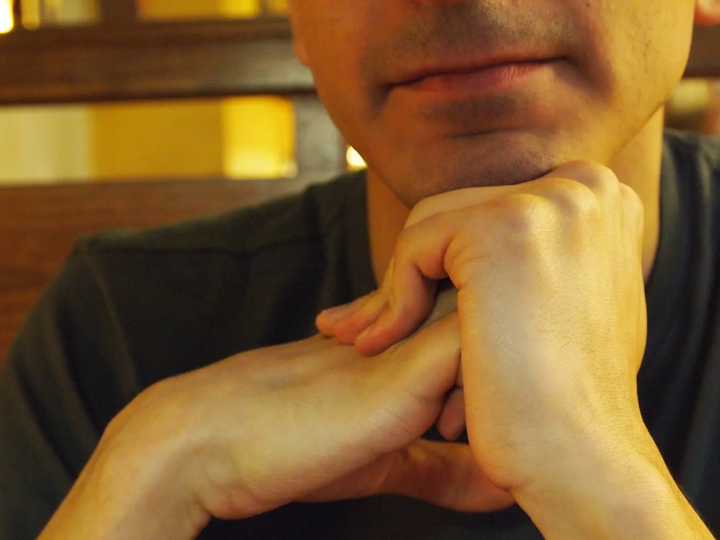 A person’s hands, one wrapped around the fingers of the other and pressing on them