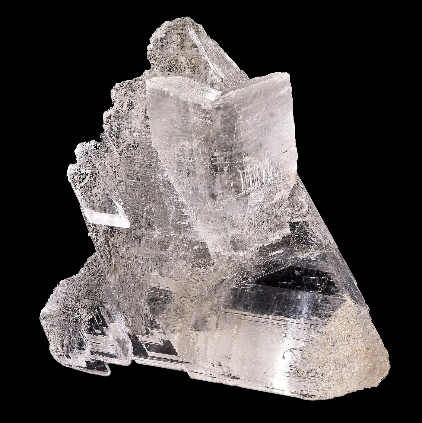 A mineral specimen of overlapping, transparent plate-like crystals against a black background