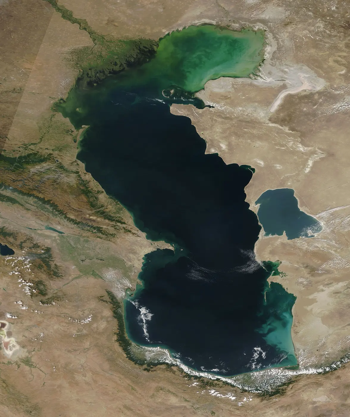 The deep blue Caspian Sea stretching north to south, surrounded by dry brown land, with its shallow northern part appearing green