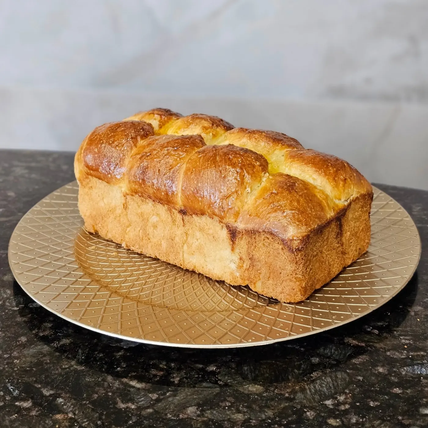 A loaf of brioche baked in a tin, with a glossy golden-brown top