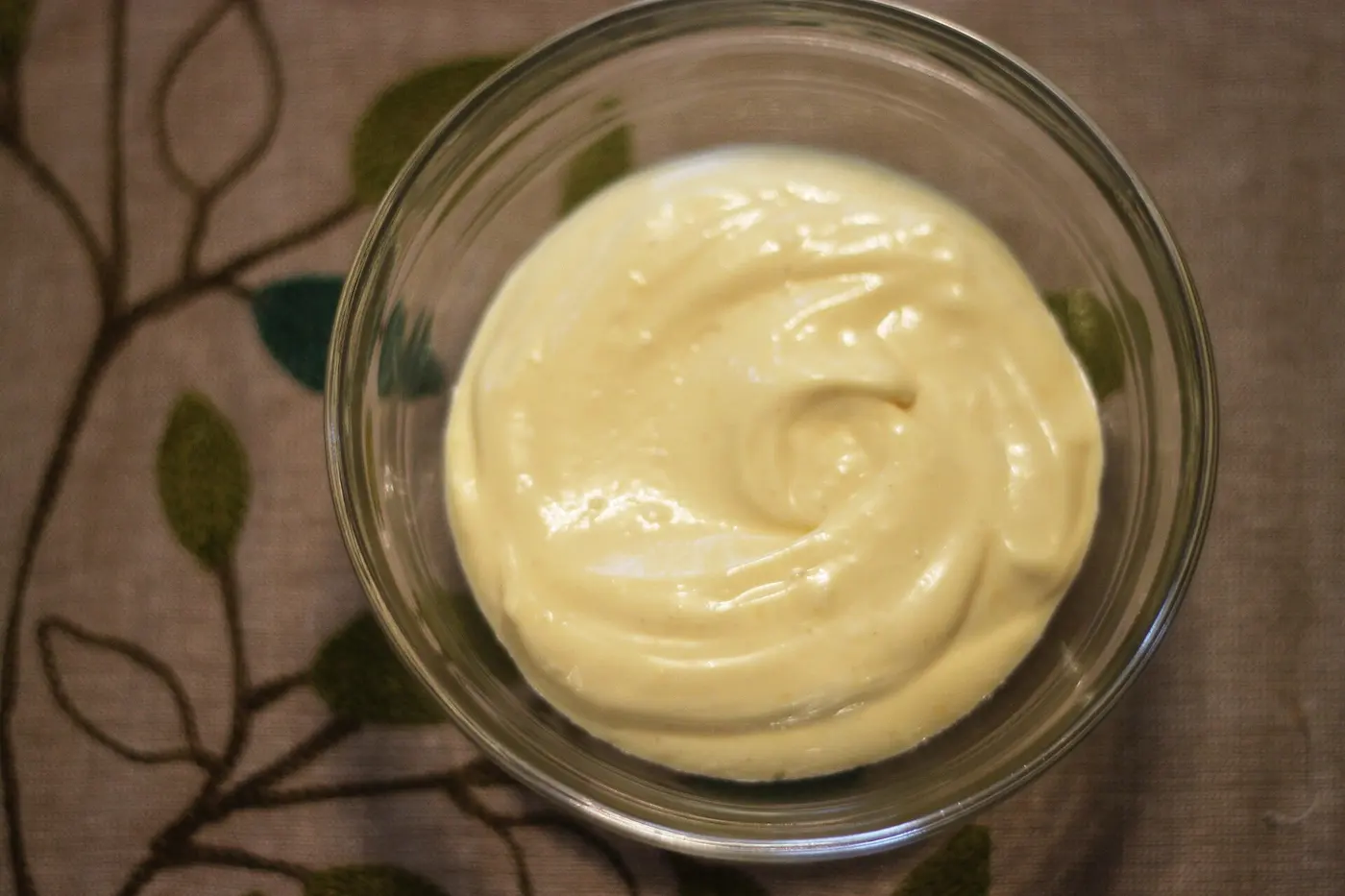 Smooth, pale yellow mayonnaise in a glass bowl