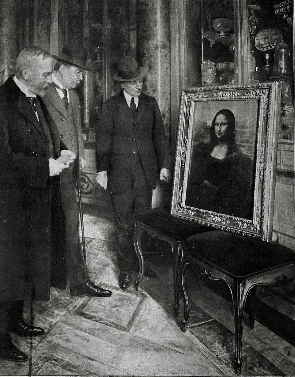 A black-and-white photo of men in suits looking at the framed Mona Lisa propped on two benches