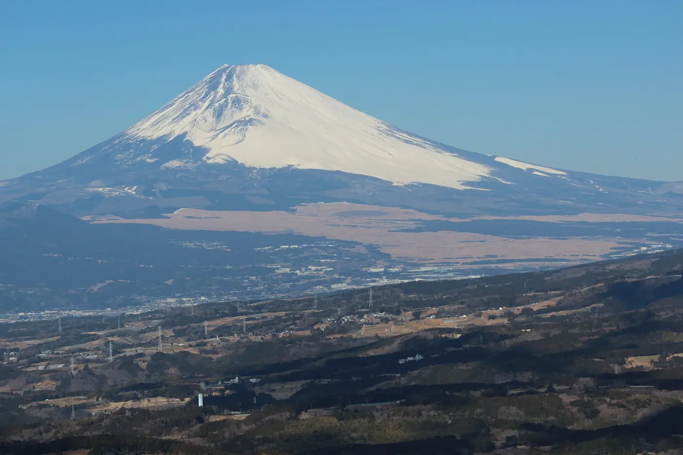 Snow-capped Mount Fuji rising above gentle lower slopes that spread out on both sides