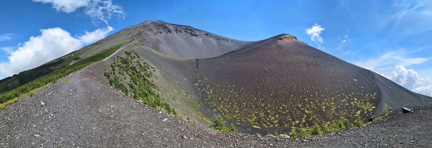 A huge bowl-shaped hollow scooped out of a mountainside, with a rise topped by reddish-brown rock towering to its right