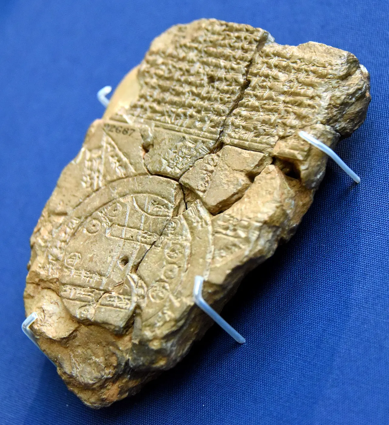 A clay tablet with cuneiform text carved on its upper half and a diagram of circles and lines on its lower half