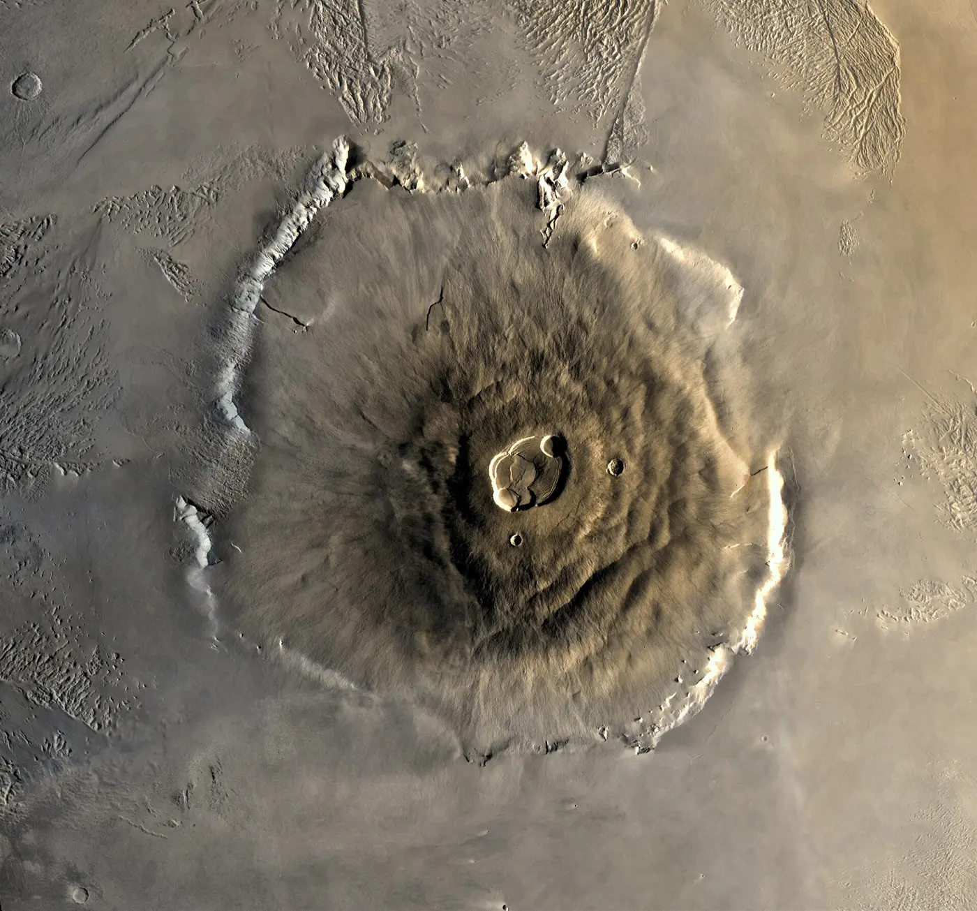 Olympus Mons on Mars seen from directly above: a broad, round mountain with a crater complex at its center and cliffs around its edge