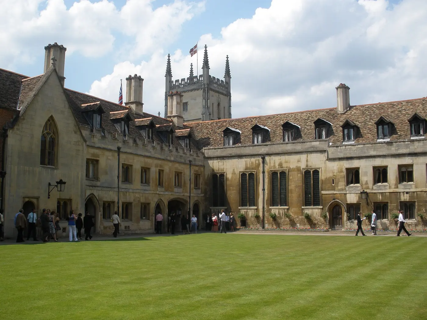 Old stone buildings and a tower around a lawn courtyard