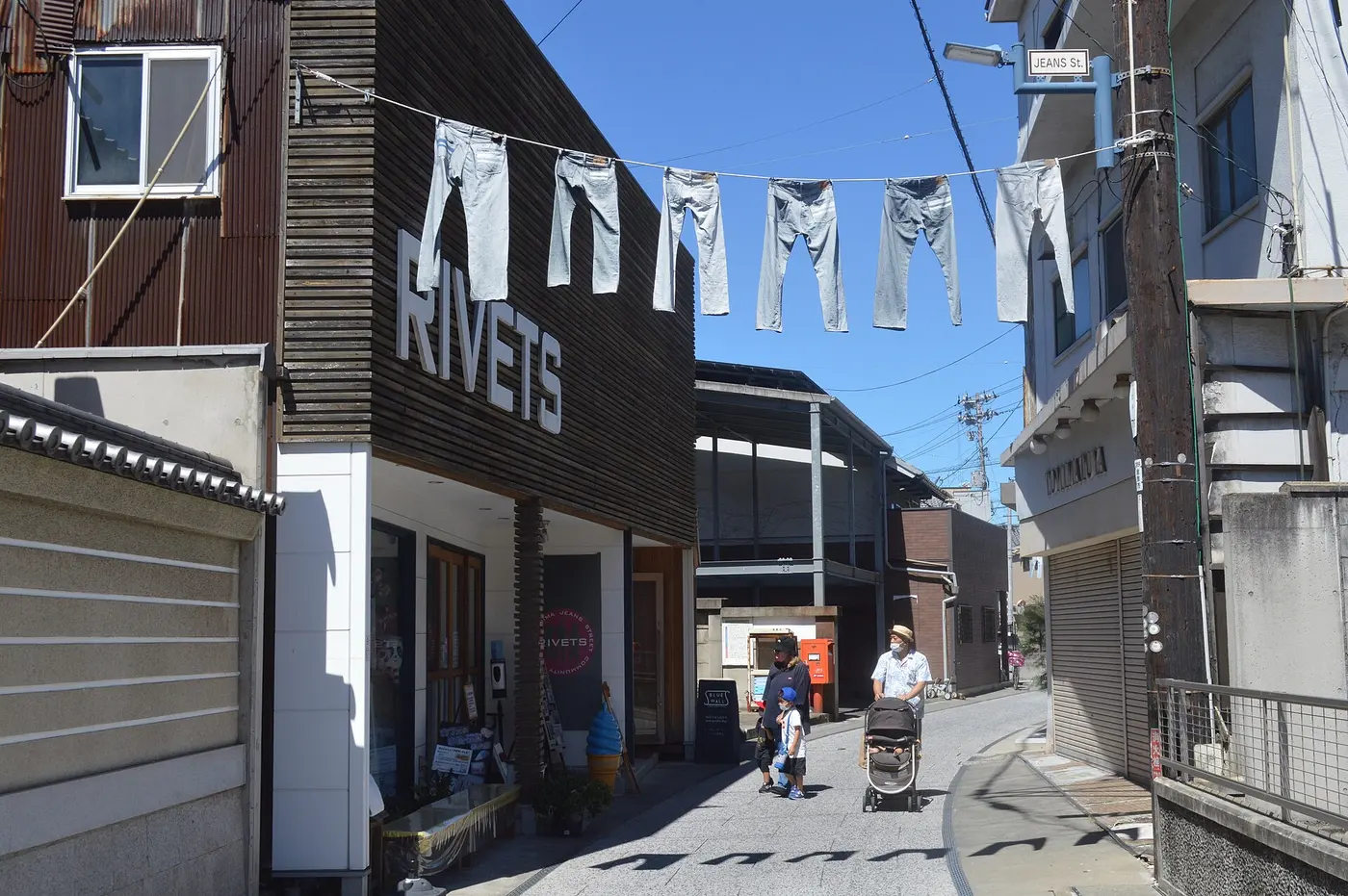 Pairs of jeans hung on ropes above a narrow street lined with shops