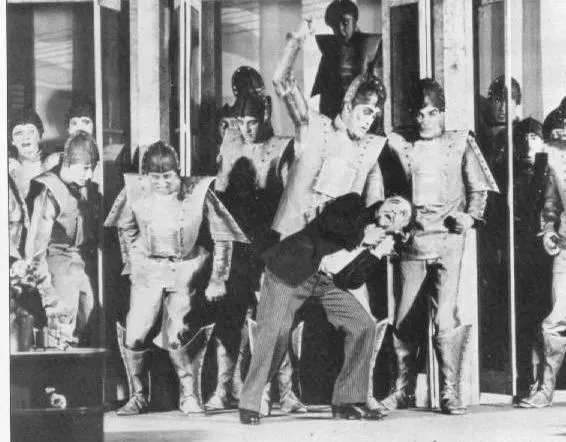 A stage photo from R.U.R. showing actors playing robots, lined up in matching costumes