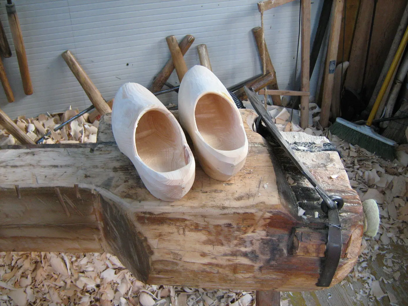 A pair of wooden shoes carved from wood, resting on a clogmaker’s workbench