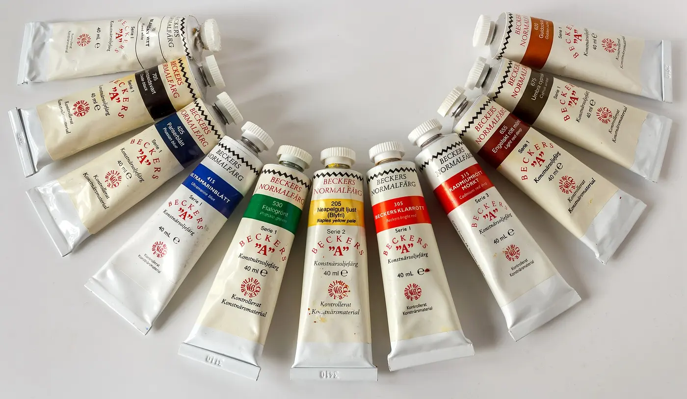 Oil paint tubes with white labels and bands of blue, green, yellow, red and brown, arranged in a fan