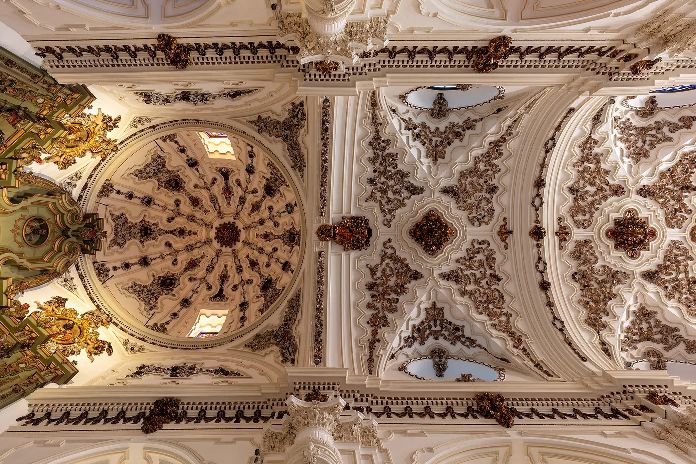 Looking up at a church interior whose white ceiling is covered in floral decoration