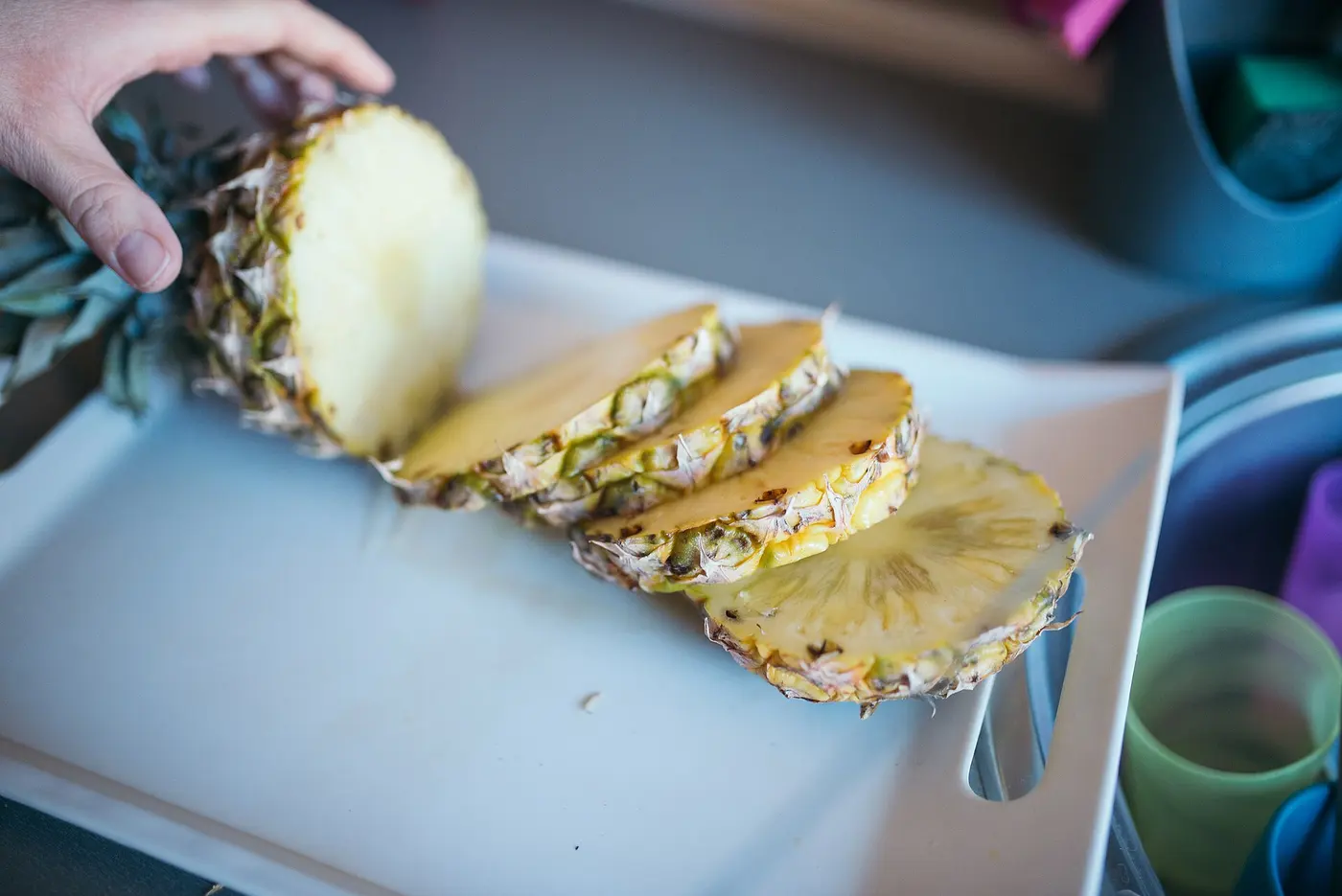 A pineapple cut into rings with the skin still on, on a cutting board