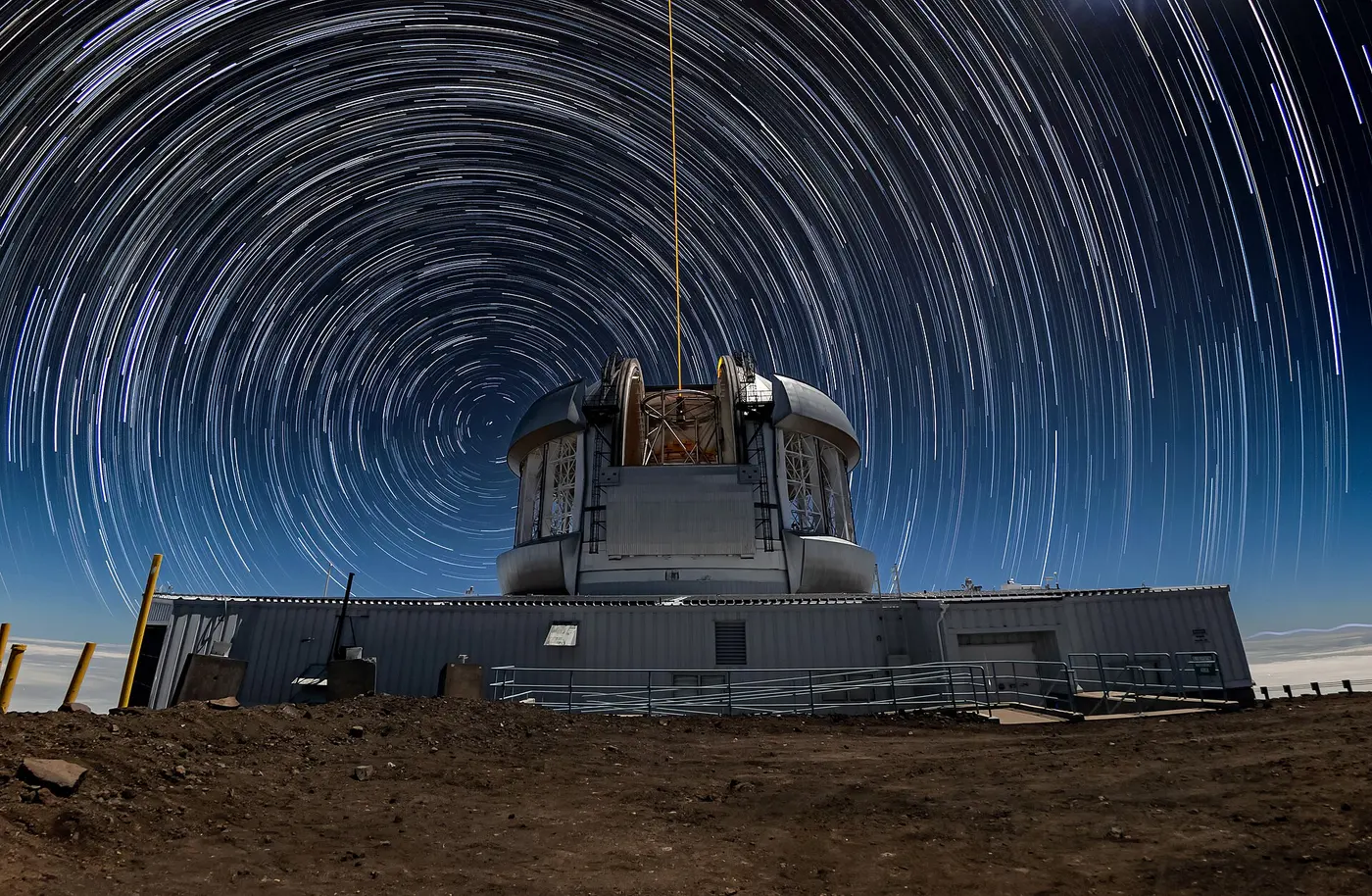 Concentric star trails circling a single point in the night sky above a telescope dome