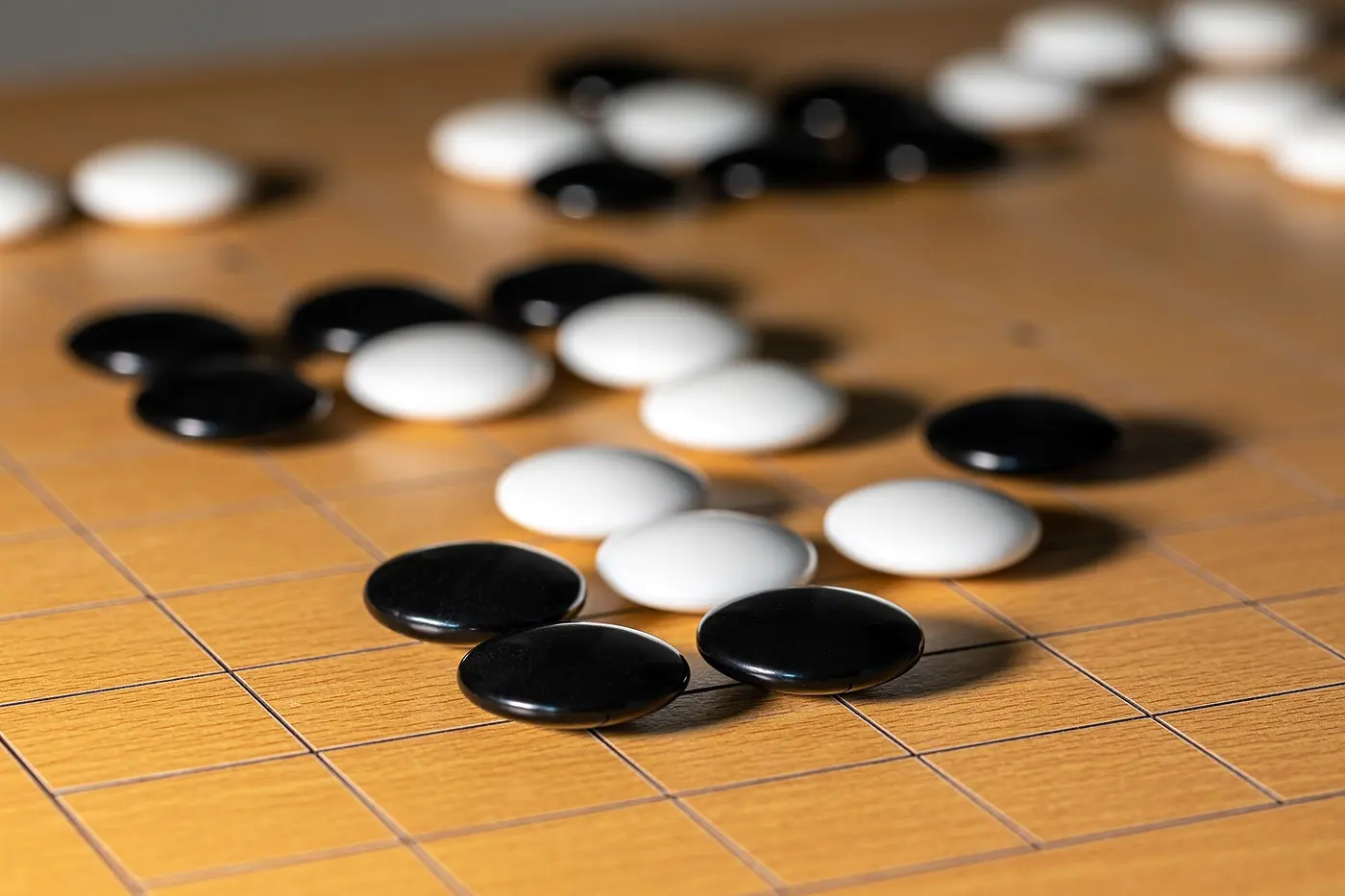 Black and white Go stones arranged on a wooden Go board
