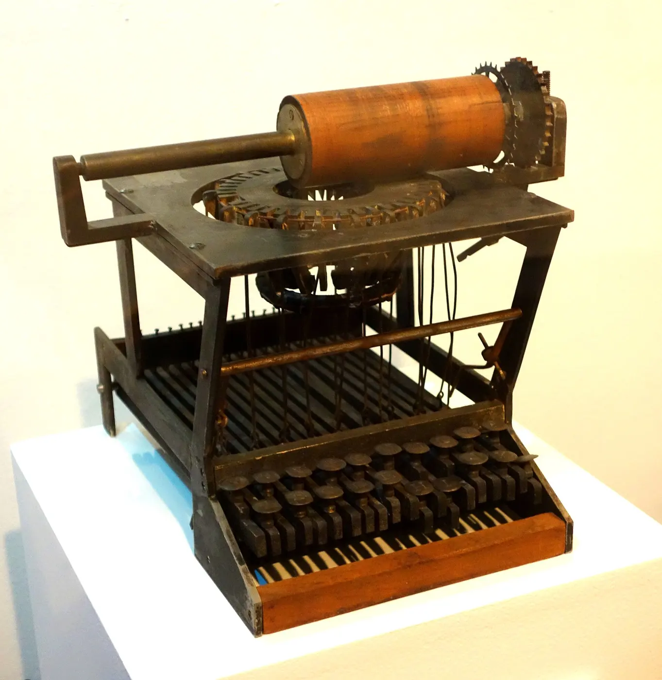 An old machine with a metal frame on a wooden base and black-and-white keys like a piano keyboard at the front