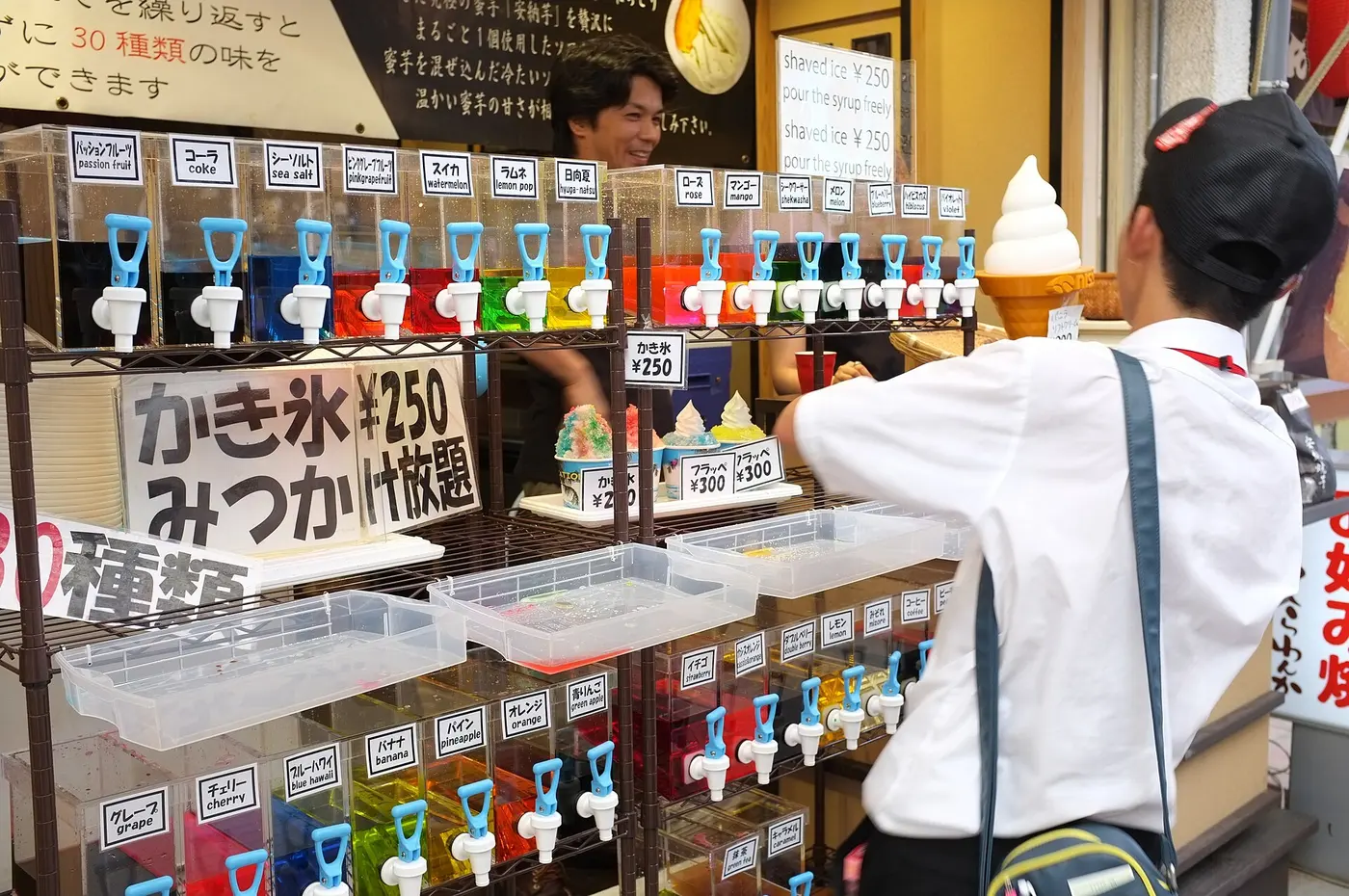 A shaved ice shopfront lined with dispensers of red, green, blue and other syrups