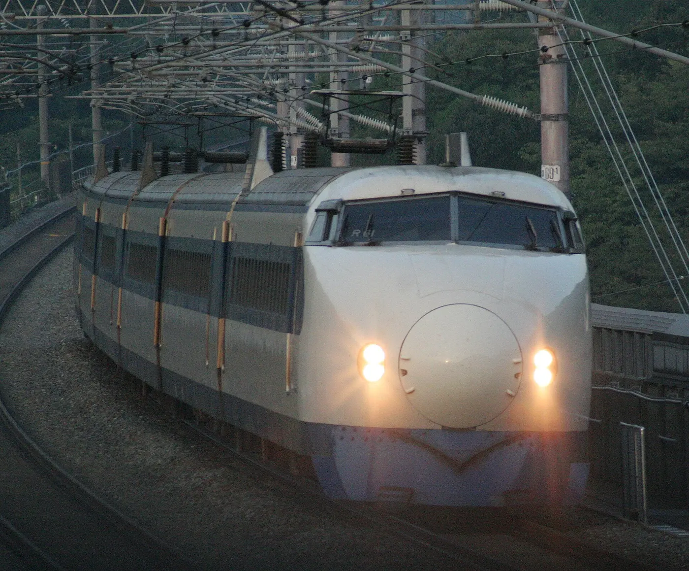 A white 0 Series bullet train with a blue stripe and a rounded, bulbous nose