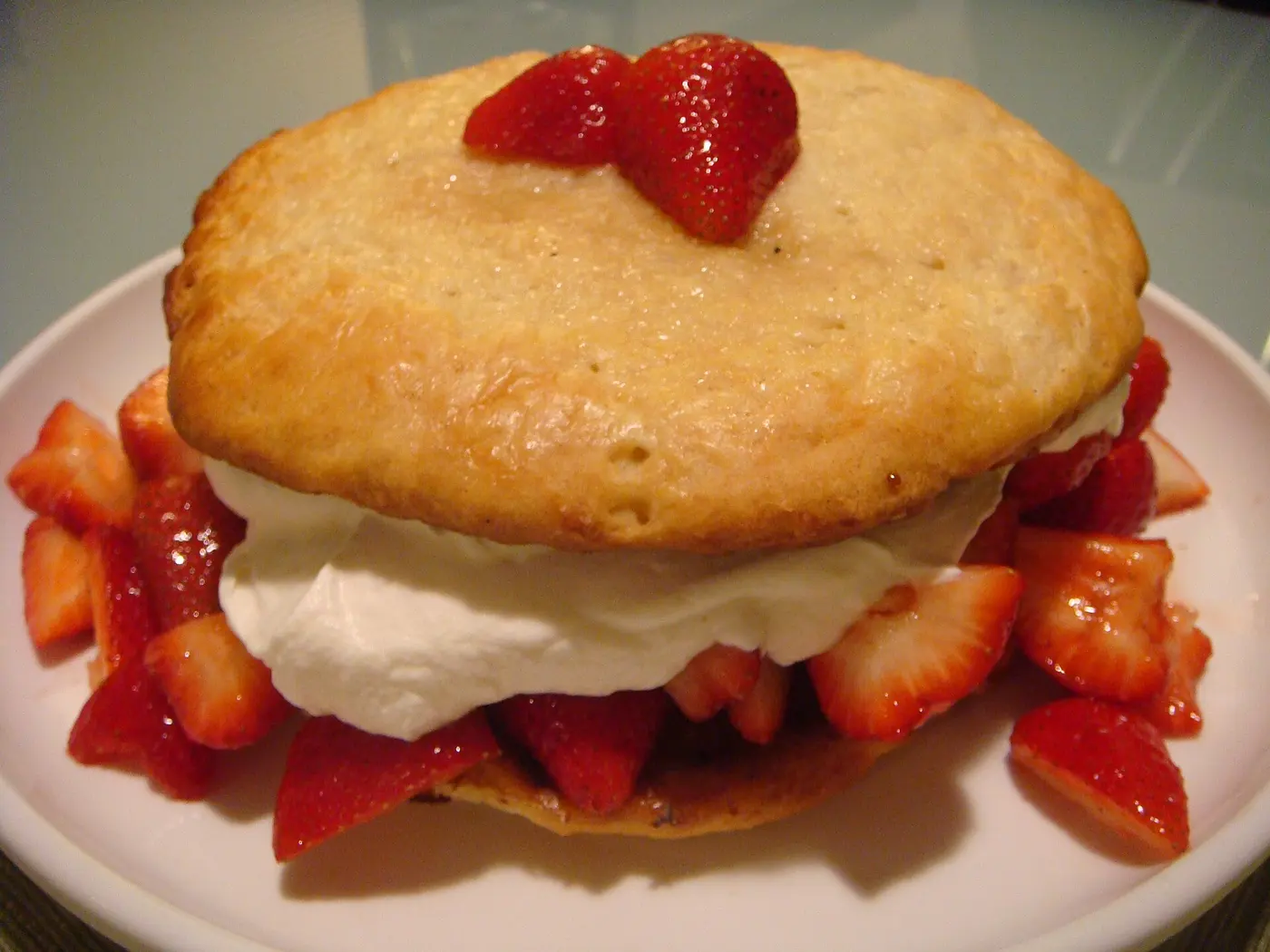An American-style shortcake: a round biscuit split in half and filled with whipped cream and cut strawberries