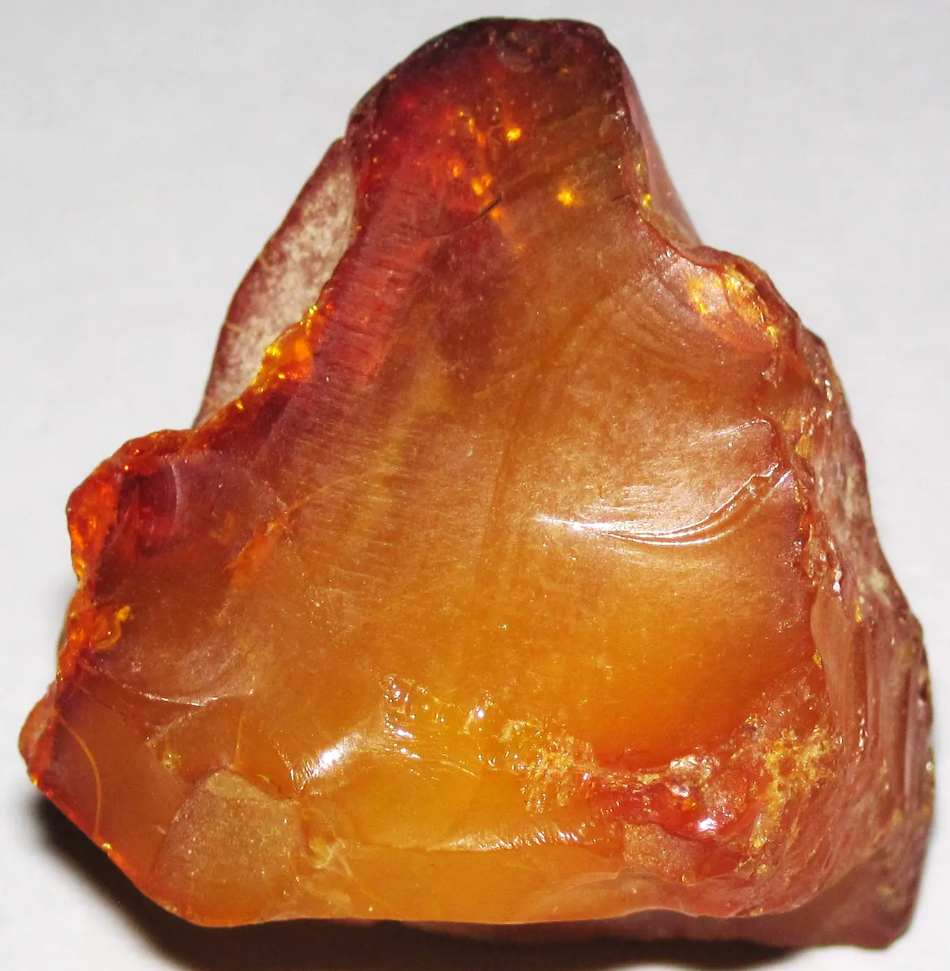 A rough, unpolished lump of translucent orange amber