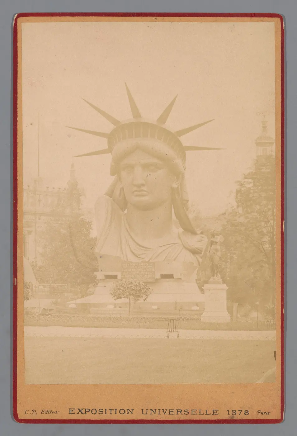 Old photograph of the giant crowned head of the statue sitting in the grounds of an exhibition