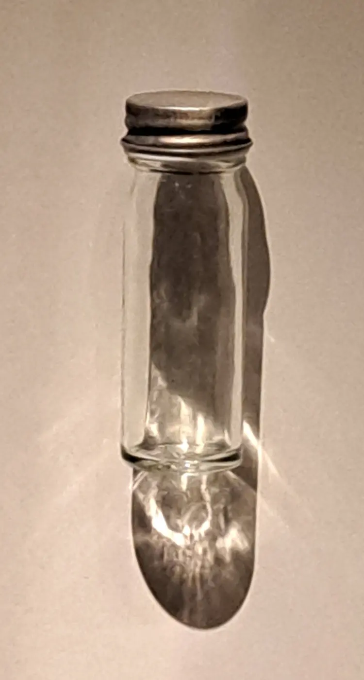 A small glass jar with a metal lid on display in a museum