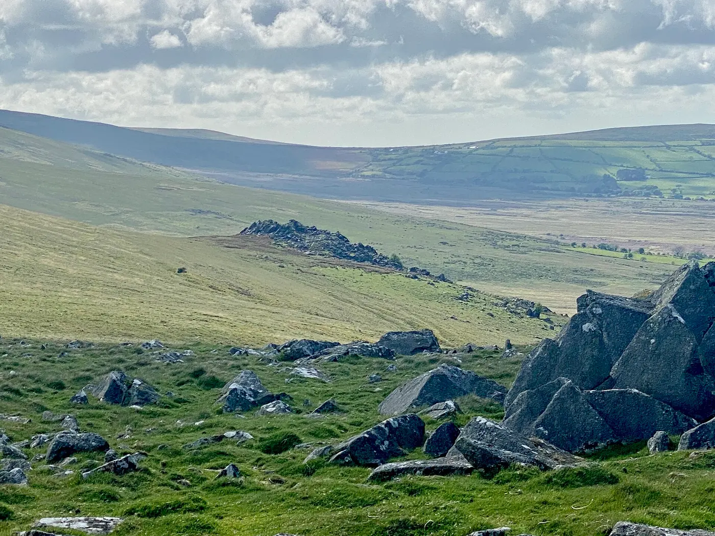 Dark piles of rock jutting out of grassy, gently rolling hills