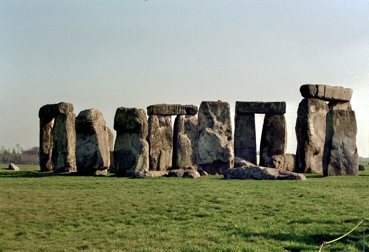 Huge gray standing stones arranged in a ring on a grassy plain, with long horizontal stones laid across the tops of some pairs