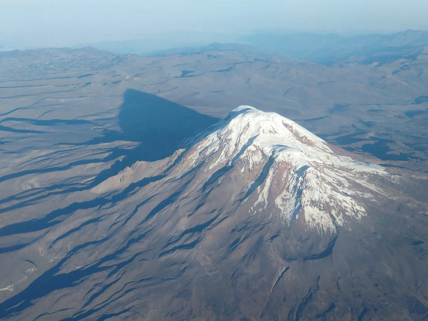 Aerial view of Chimborazo, its glacier-covered summit casting a long shadow over the dry land below
