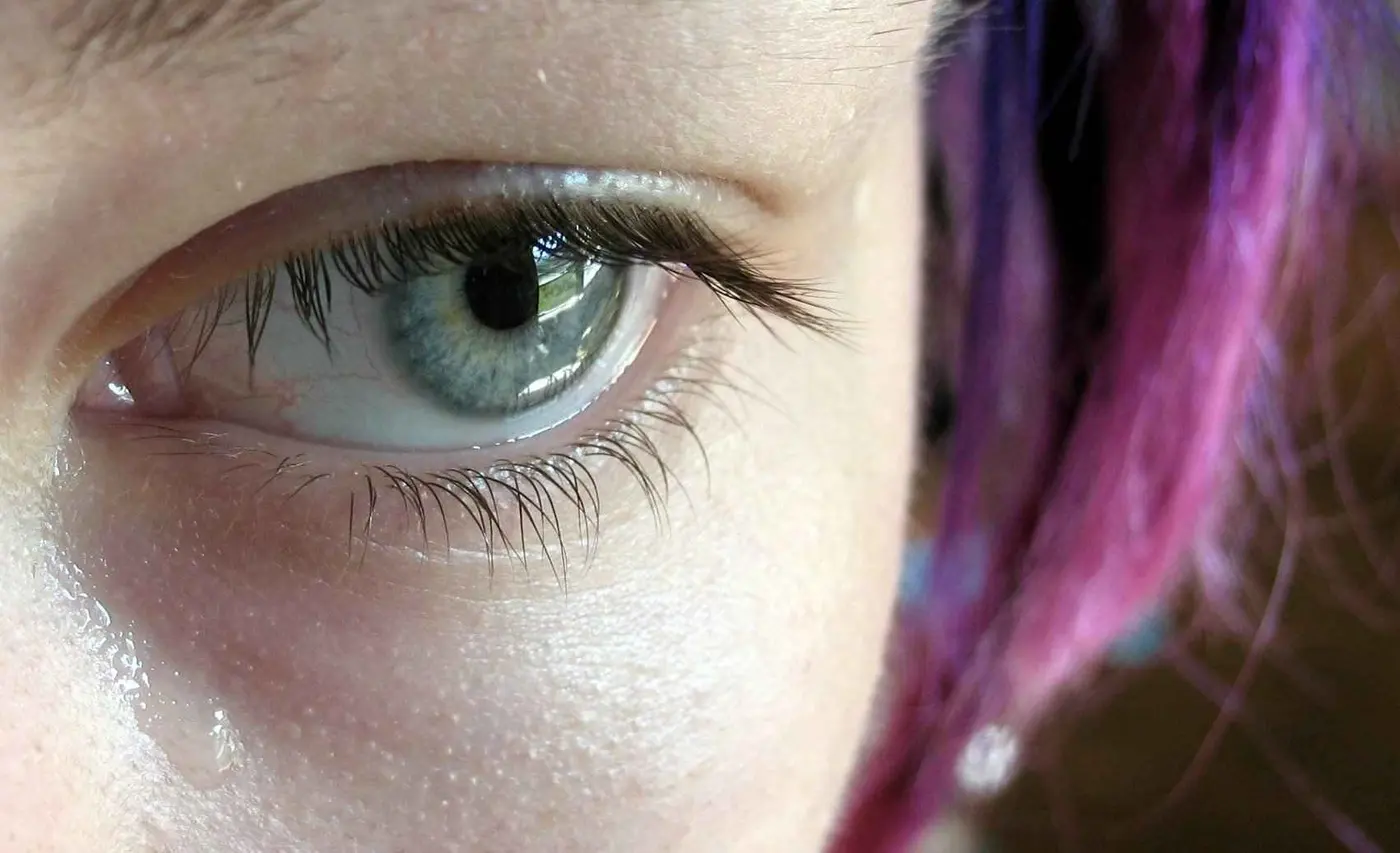 Close-up of an eye, with the cheek below glistening with tears