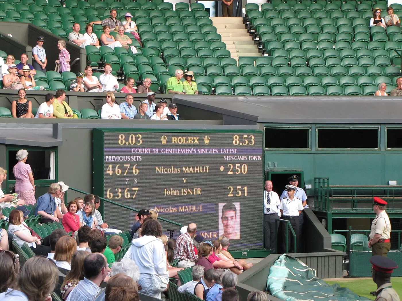 An electronic scoreboard in front of the Wimbledon stands, showing the score partway through the Isner–Mahut match